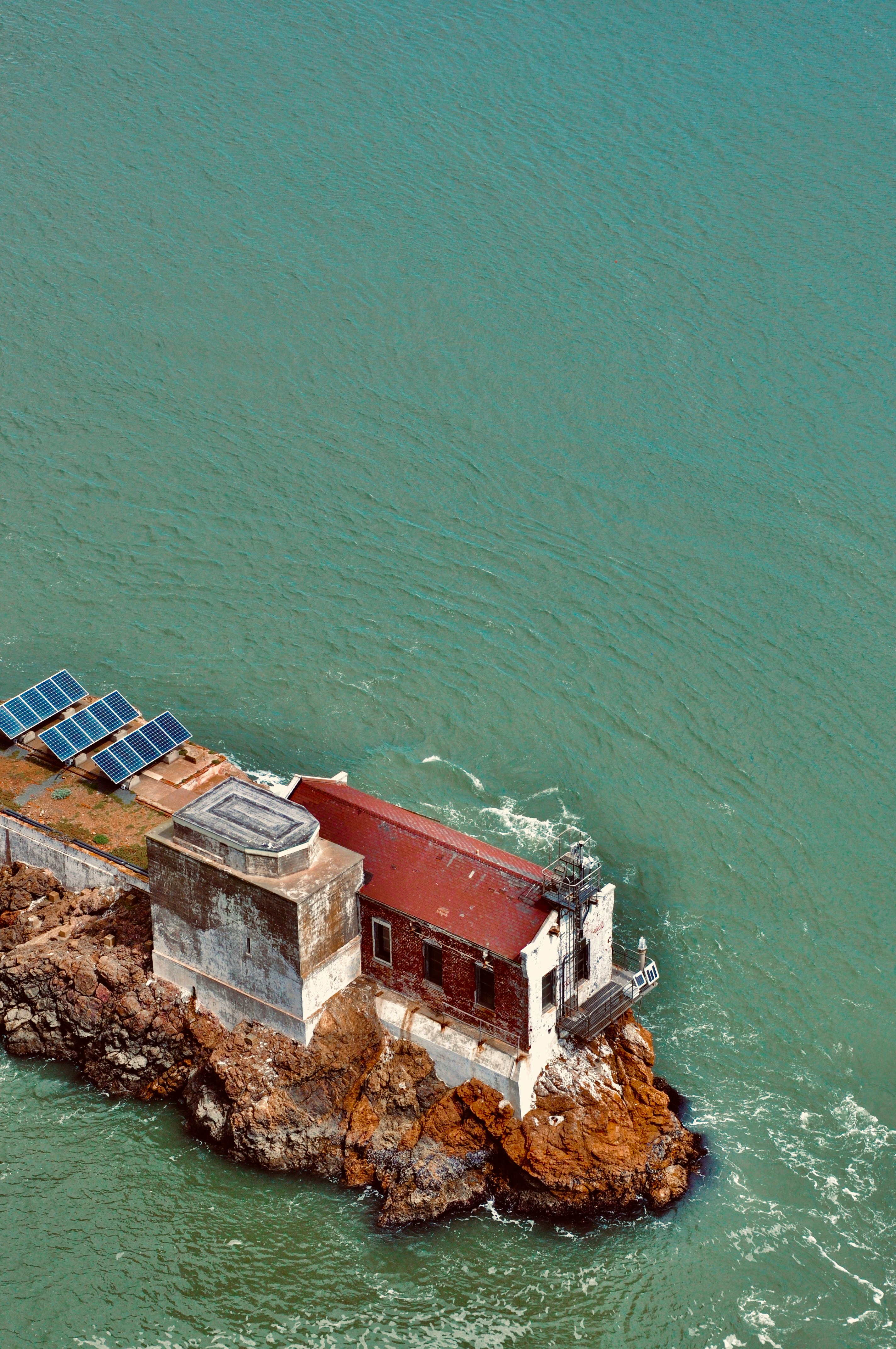 aerial view of red and white house beside body of water during daytime